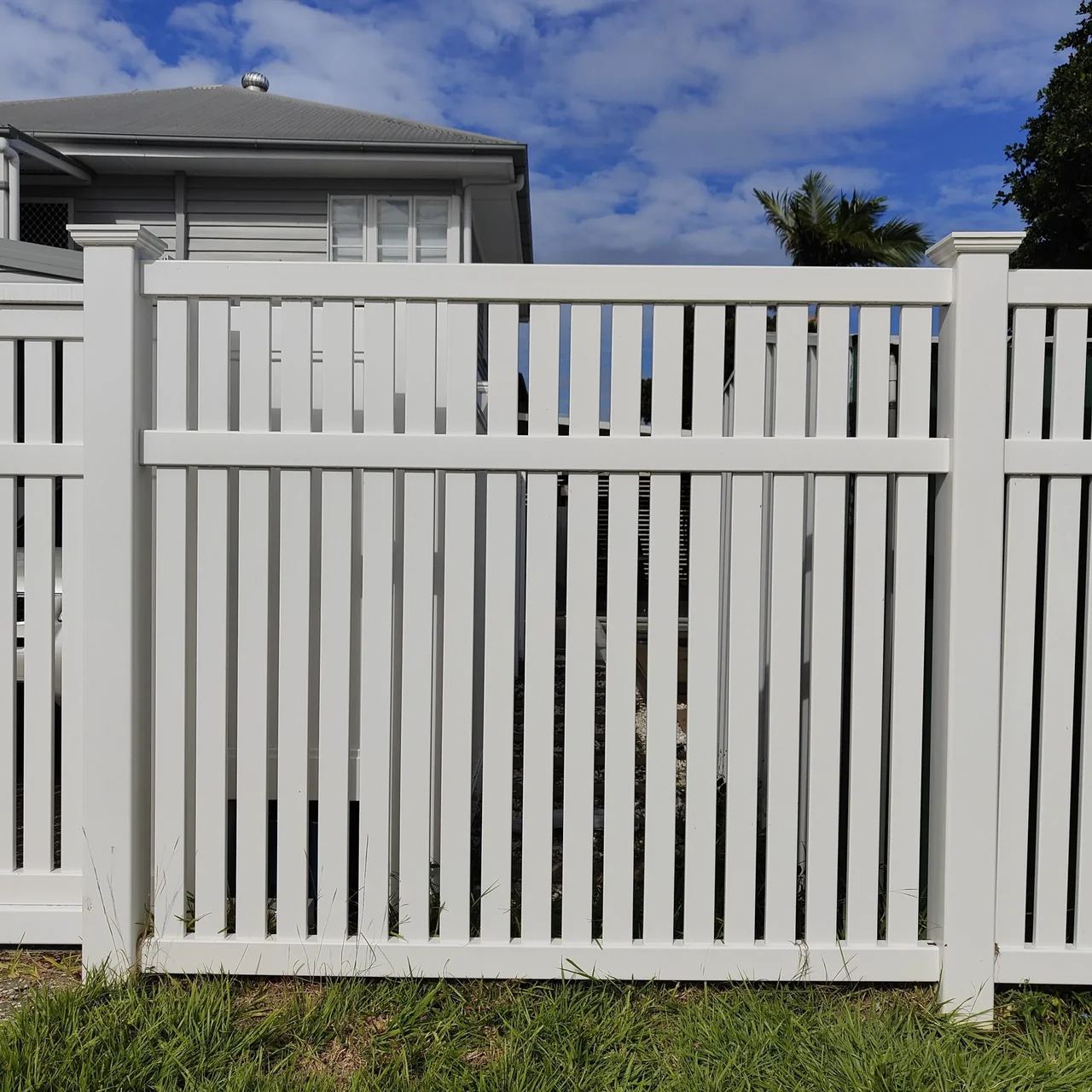 Close view of a white semi-privacy fence with spaced vertical slats and gaps between them
